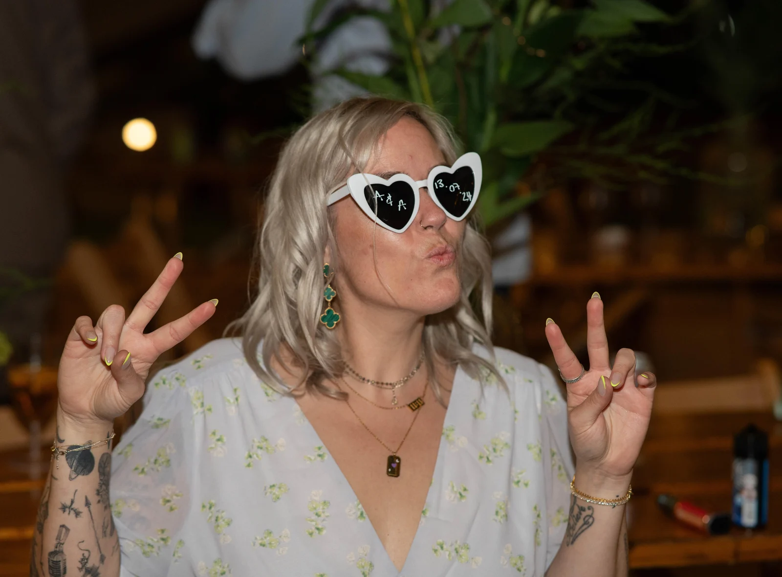 A wedding guest in heart-shaped sunglasses pulling a peace sign on the dance floor