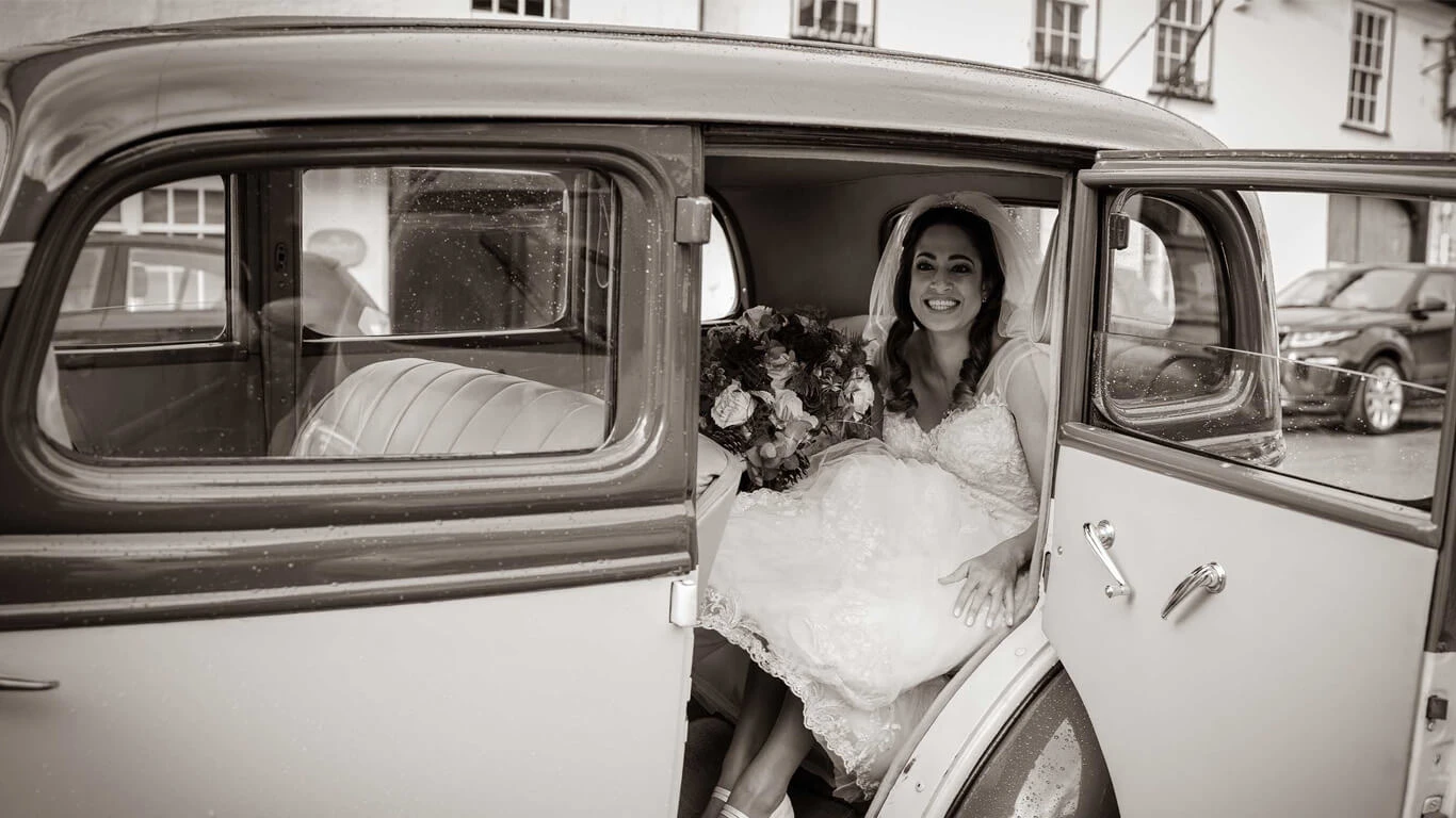 Natasha smiling from the open door of her wedding car