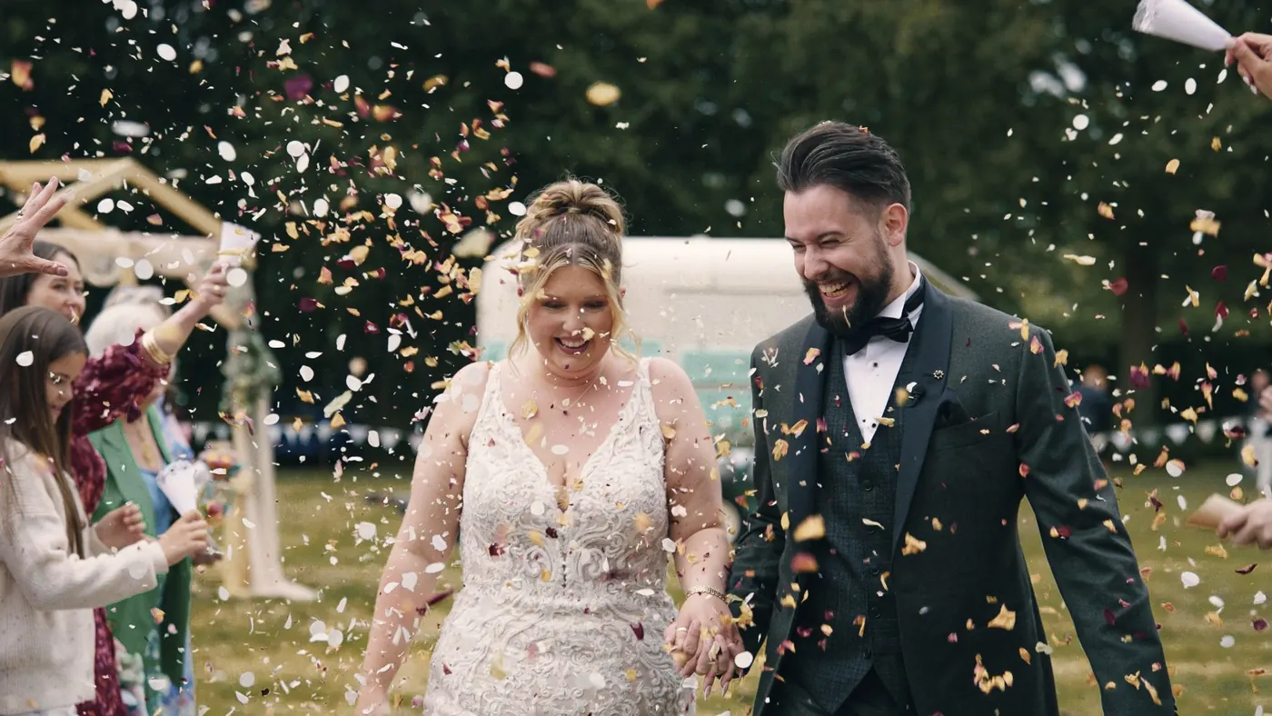 Couple walking through a shower of confetti after the ceremony