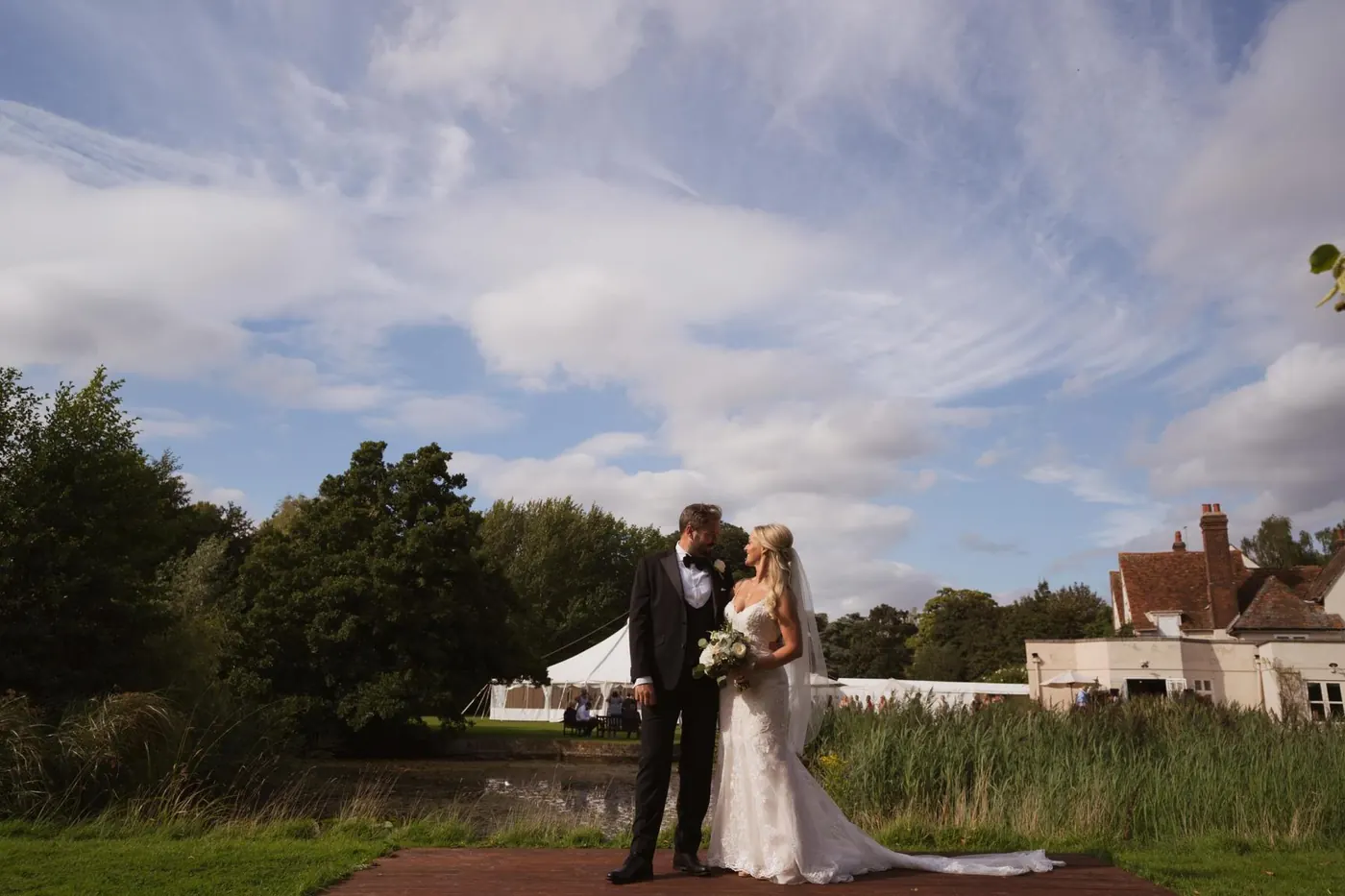 Wide shot of a couple kissing beneath dramatic clouds