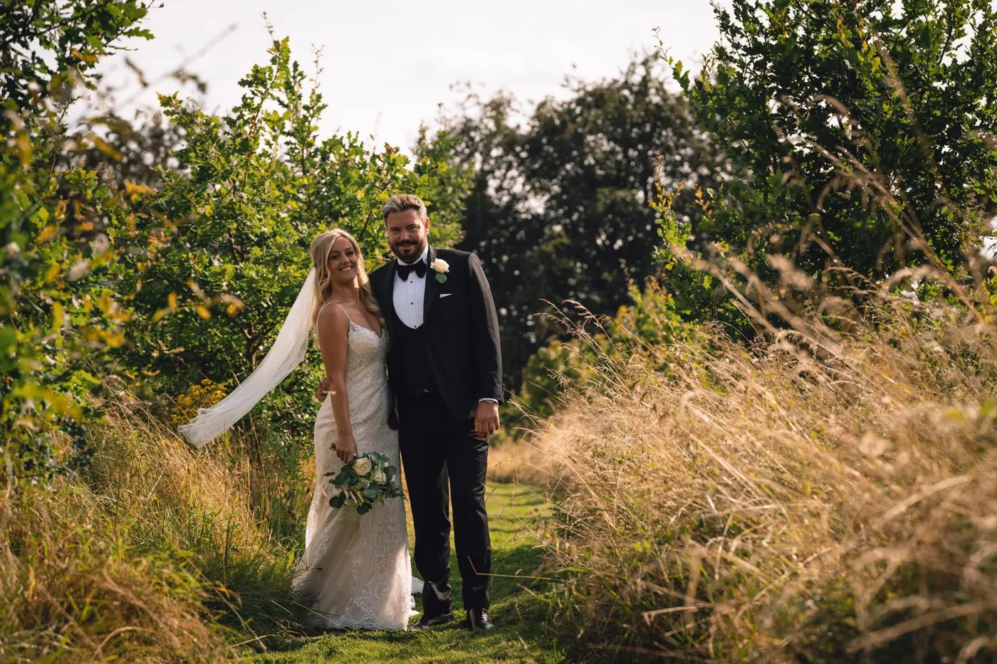 Couple standing in long golden grass at sunset