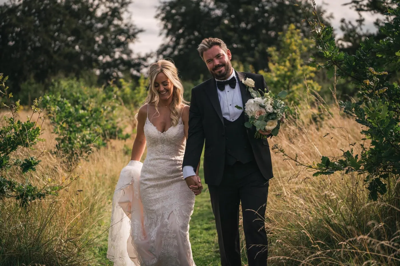 Couple walking hand in hand through a meadow