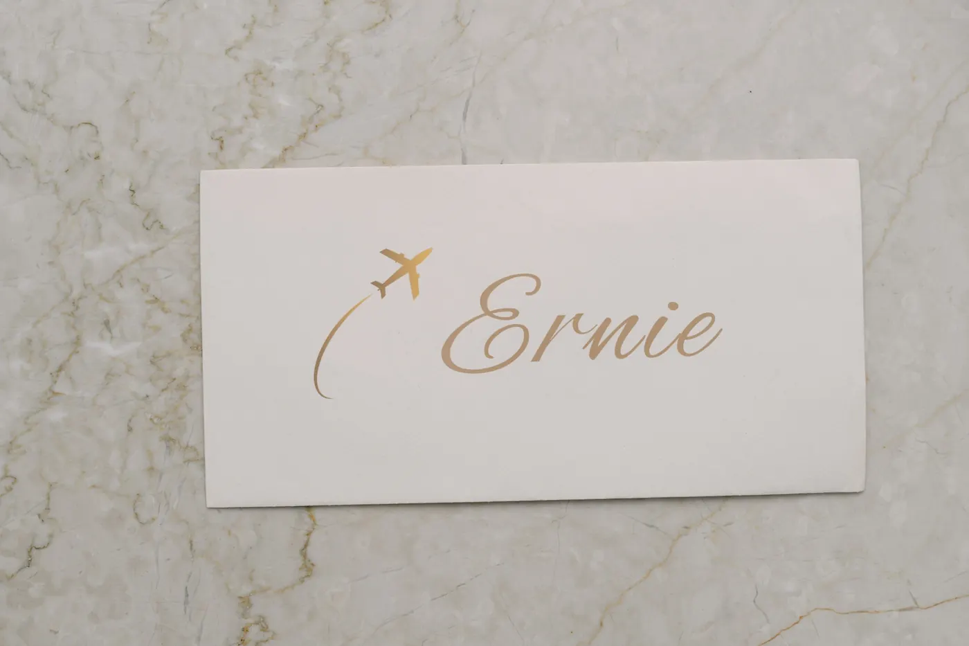 Gold foil place card with a small aeroplane and the groom's name
