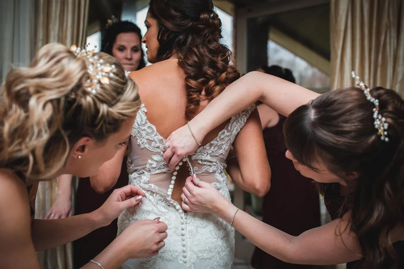 Bridesmaids lacing up the back of a wedding dress