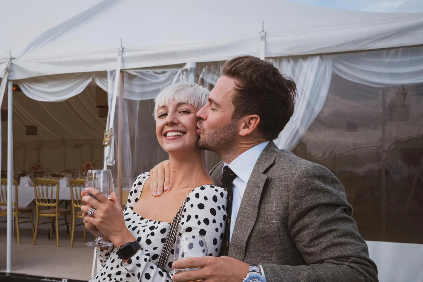 Guests sharing a kiss on the cheek outside the marquee