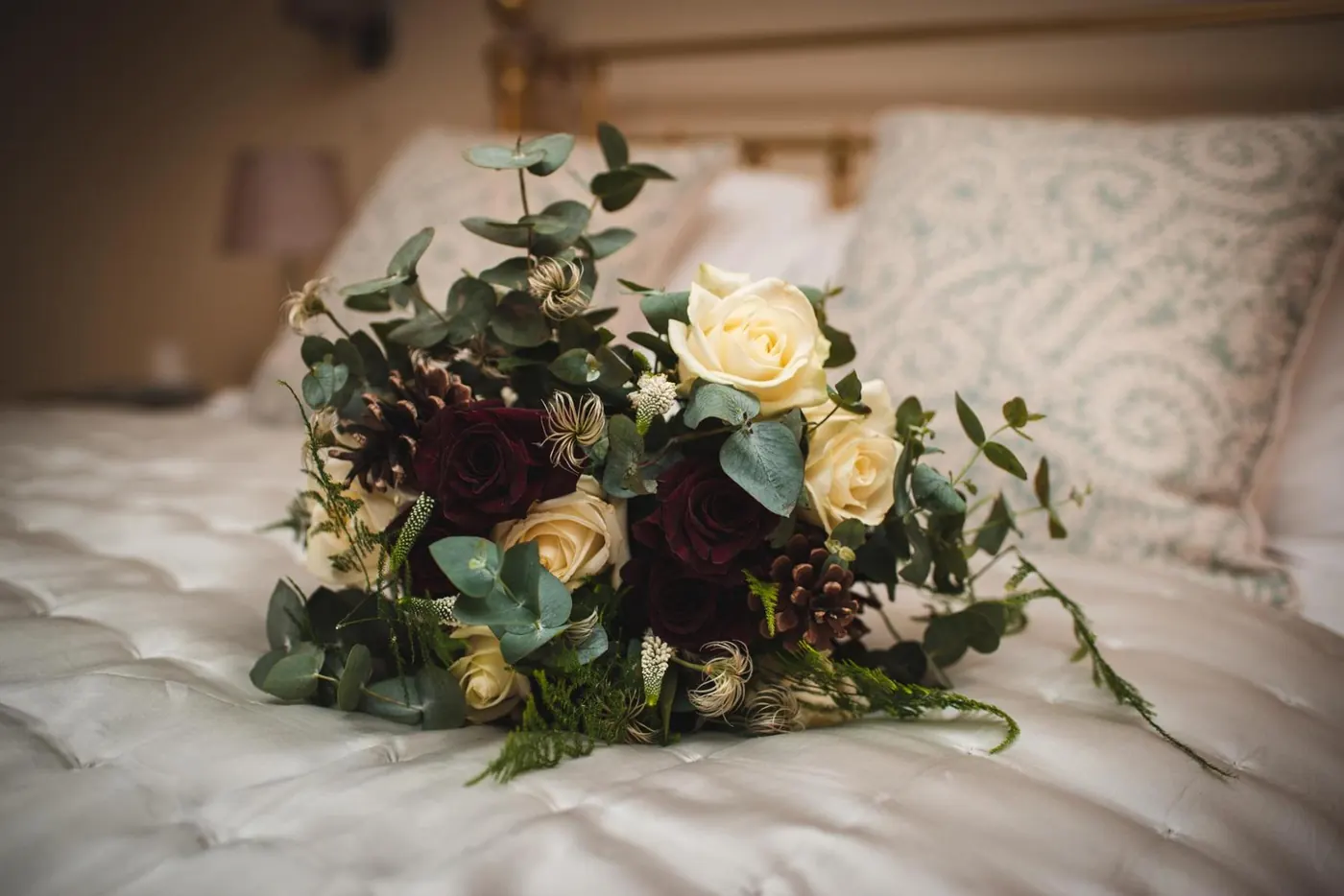 Winter bouquet of burgundy and ivory roses resting on a bed