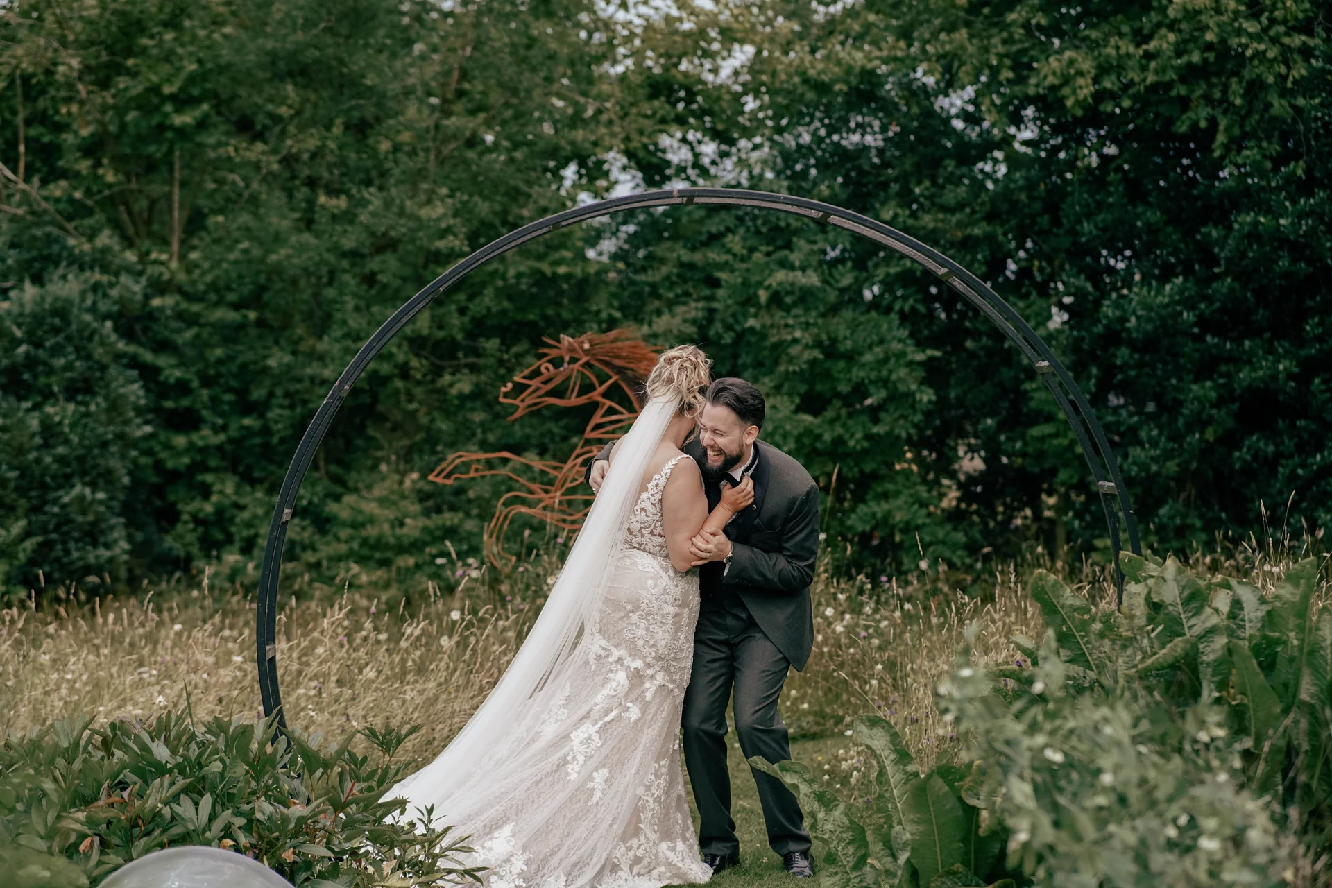 Alice and Alex kissing beneath a garden arch