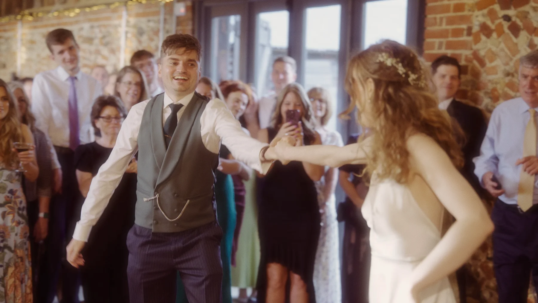 Charlotte and Dom dancing in the barn with friends and family watching