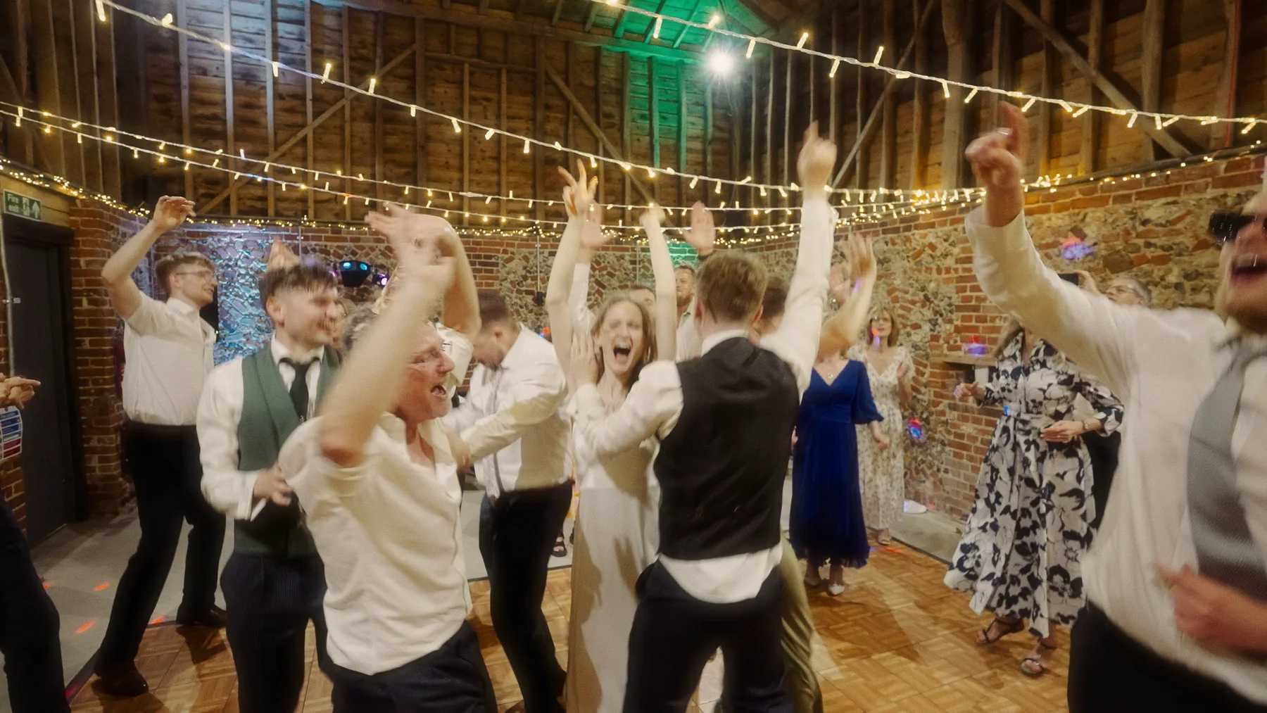 Charlotte and Dom’s guests with their hands in the air beneath the barn lights