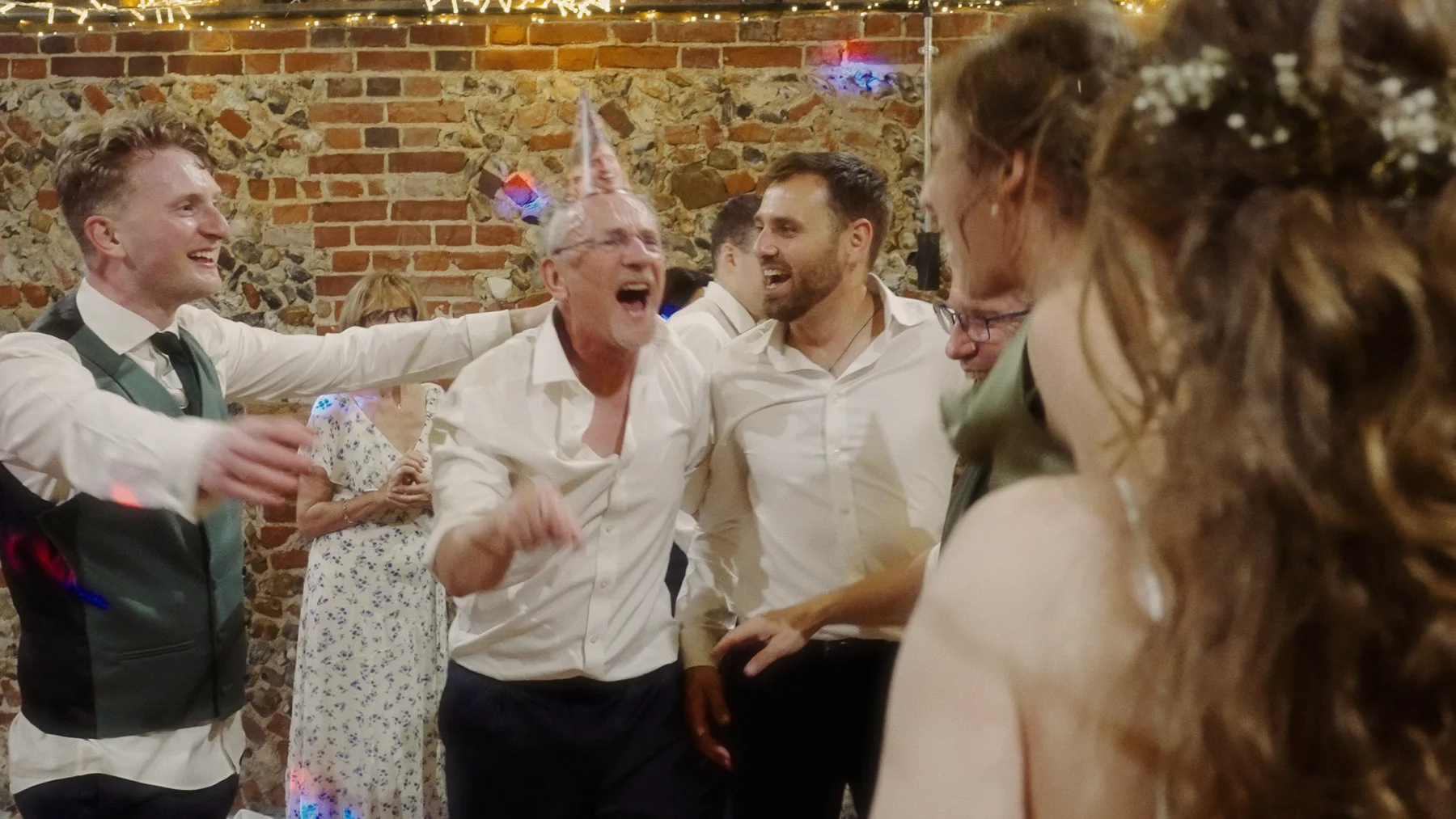 Wedding guests singing and dancing together in the barn