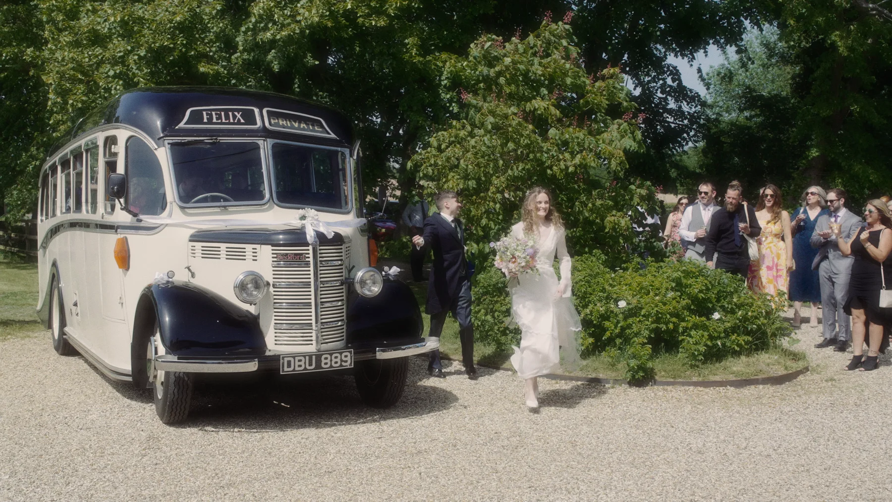 Charlotte and guests beside a vintage cream and dark blue bus at Old Hall